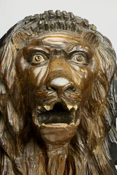 The face full on, eyes wide under a heavy brow, the open jaws showing carved teeth and a broad tongue.
