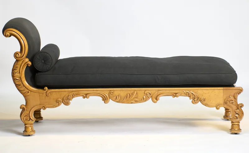 A carved daybed with scrolled end