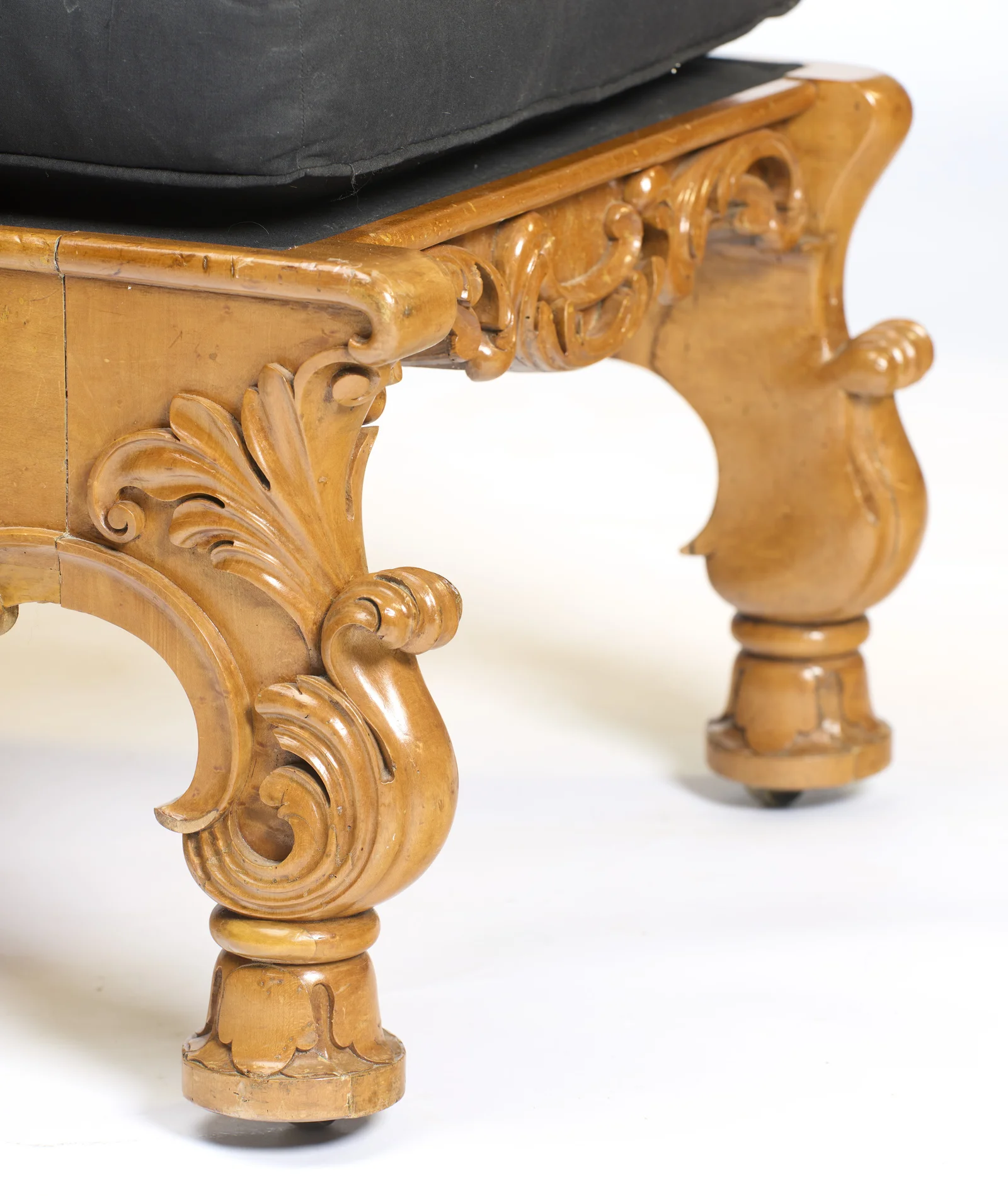 The S-scroll bracket leg is carved with sweeping leaves and ends in a turned, lappet-carved foot on a small castor.