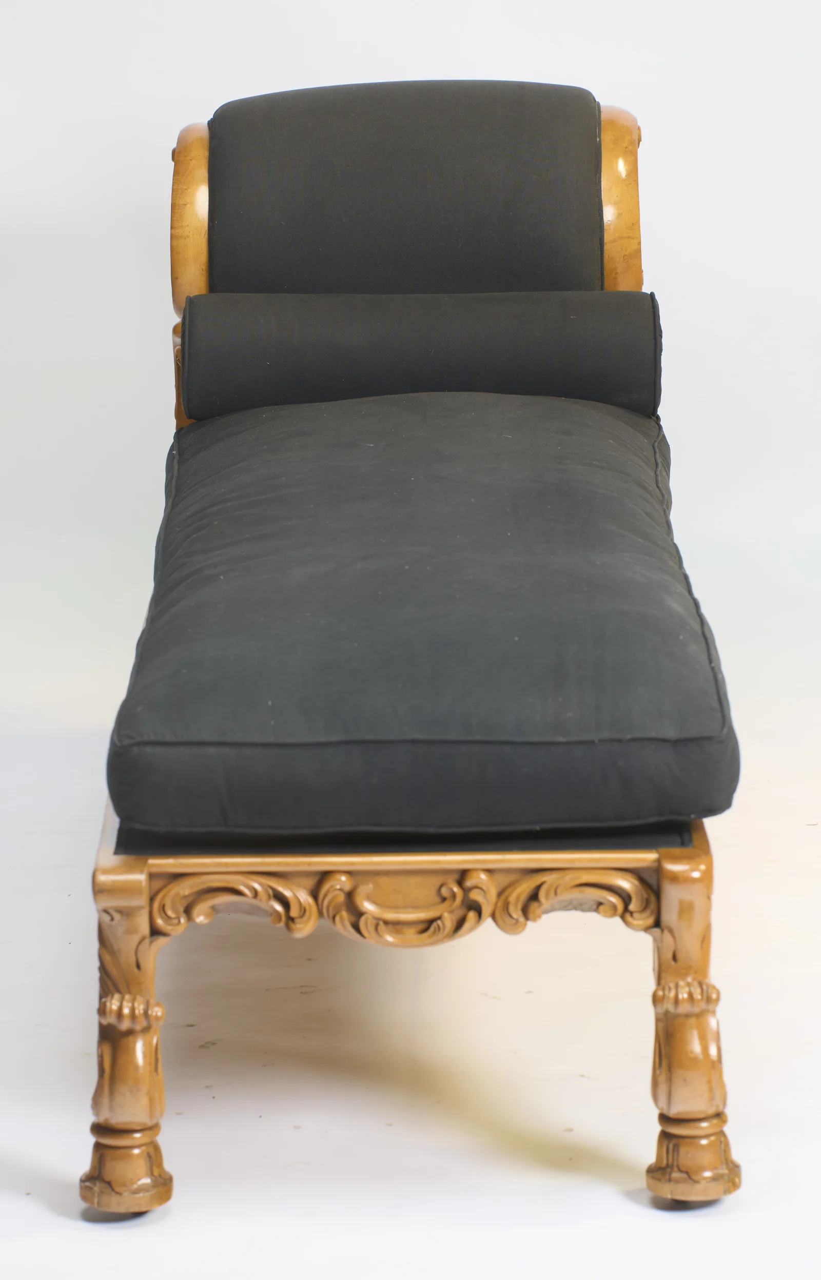 The upholstered crest and bolster face straight down the seat, with the carved apron and feet of the foot end in the foreground.