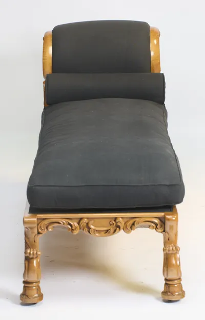 The upholstered crest and bolster face straight down the seat, with the carved apron and feet of the foot end in the foreground.