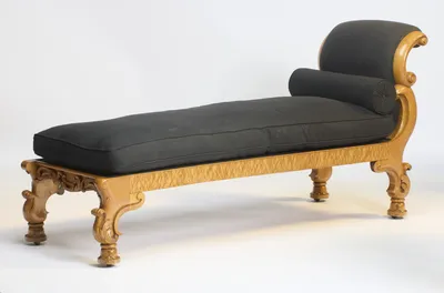 Seen from the foot corner, the plain figured rail runs to the scrolled head end, where the bolster's pleated rosette just shows.