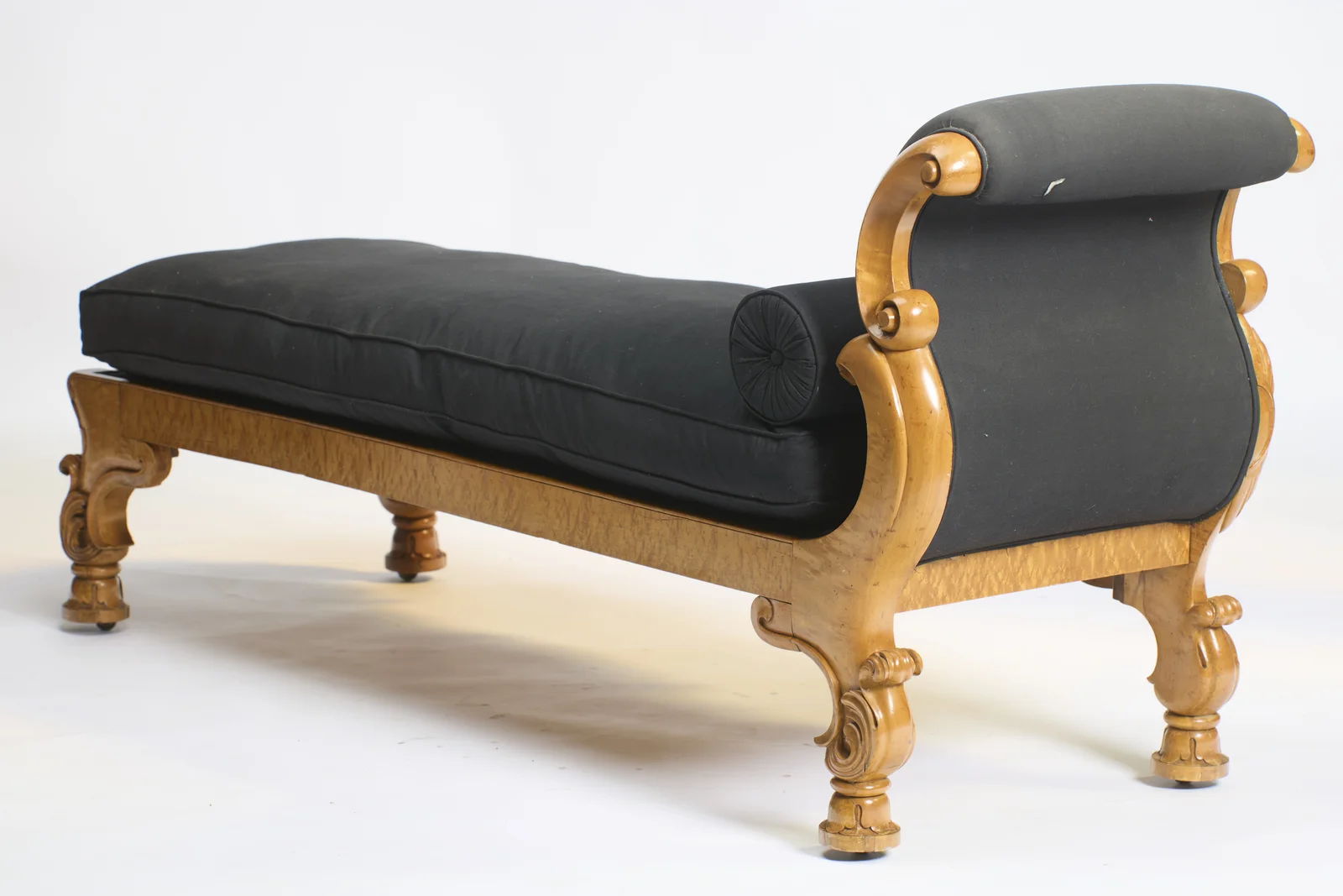 The black outside back sweeps up to the rolled crest between scroll-carved supports and legs.
