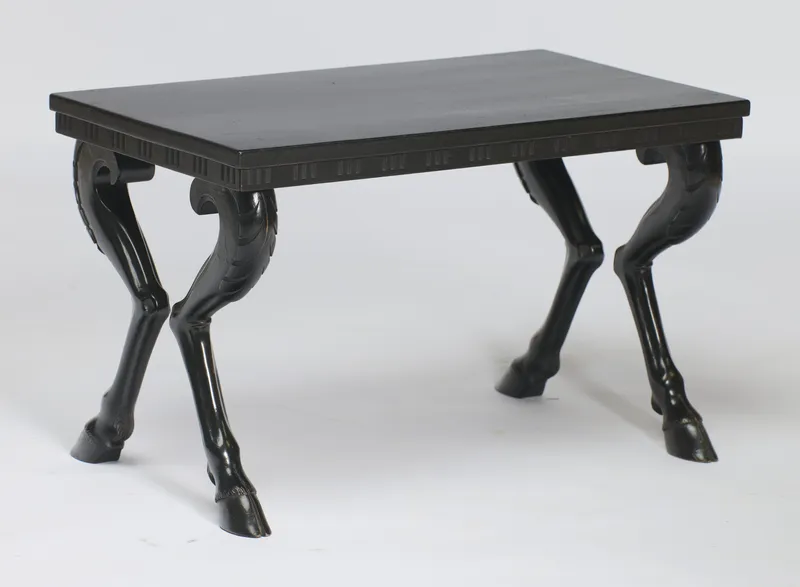 An ebonised low table on cloven-hoofed animal legs