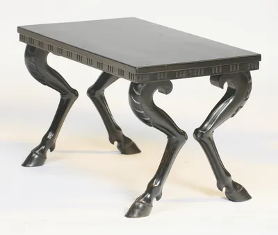 The top recedes to show the legs kicking outward in pairs, each haunch curling into a scroll beneath the frieze edge.