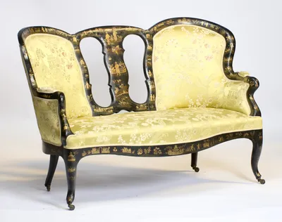 The scrolled arm and shorter back stand nearest, with the taller winged back rising beyond the pierced splat.
