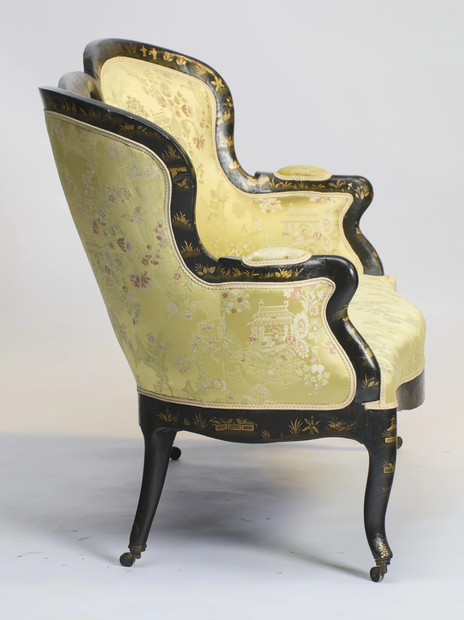 The out-scrolled arm descends over an outside back upholstered in the same figured damask, within black borders painted with gilt sprays.