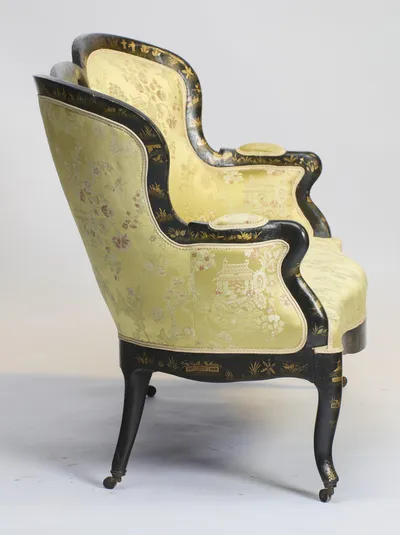 The out-scrolled arm descends over an outside back upholstered in the same figured damask, within black borders painted with gilt sprays.