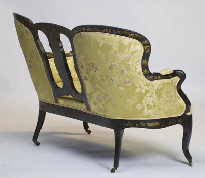 The pierced splats read against the damask seat, the outside back and arm scroll beyond.