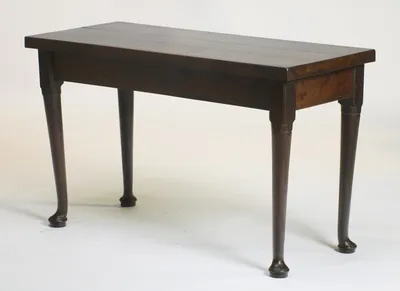 A higher viewpoint across the top, taking in the end rail, the carved lappets heading each leg and the joint line running the length of the top.