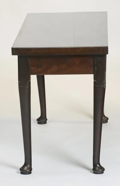 The short side, showing the overhang of the top past the frieze and the taper of the legs to their pad feet.
