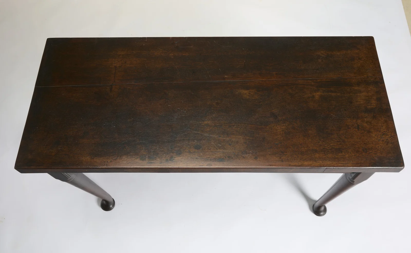 The two-board top from above, with an open joint line between the boards and scattered scratches and marks in the dark polished surface.