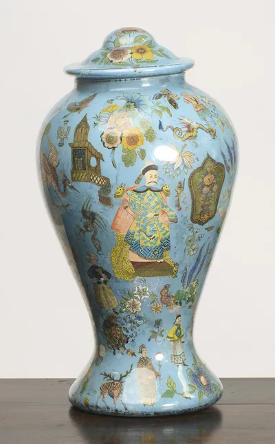 A moustached figure in a blue and yellow dragon robe sits enthroned at the centre, with a stag and further small figures around the waisted foot.