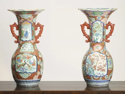 Both vases together, trumpet necks with scalloped gilt-edged rims, coral-red scroll handles, and panelled decoration reserved on an iron-red ground.