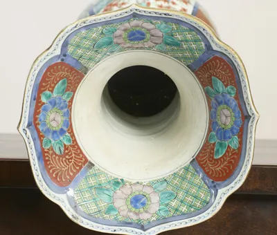 Flowerheads on a green trellis alternate with red foliate panels around the scalloped, gilt-edged mouth, and the interior of the neck is plain white.