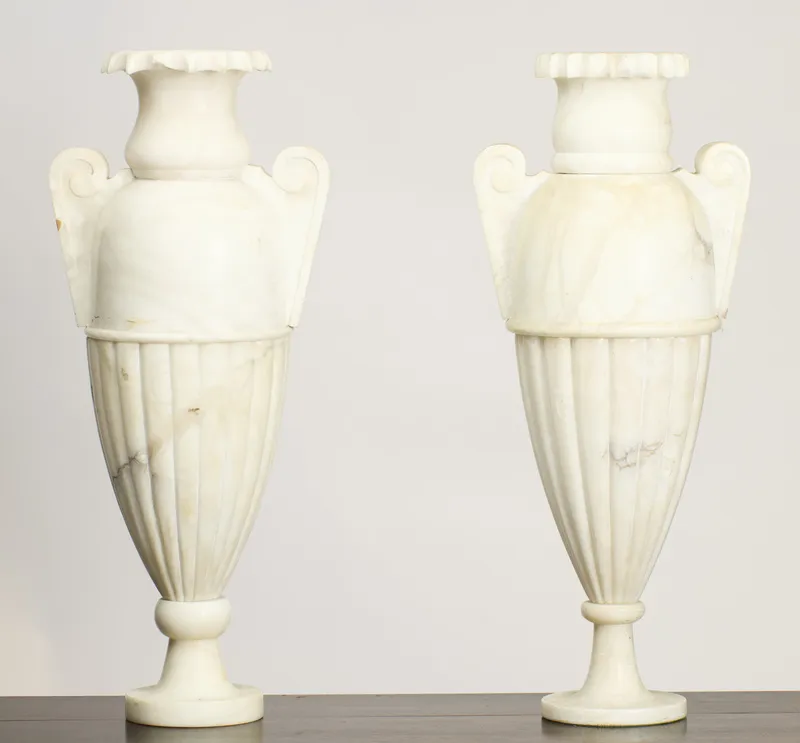 Pair of veined white stone urns with scroll handles and fluted bodies