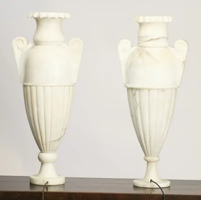 Pronounced grey veining crosses the neck and shoulder of the right-hand urn, whose panels between the handles show a stippled texture against the smooth left-hand urn.