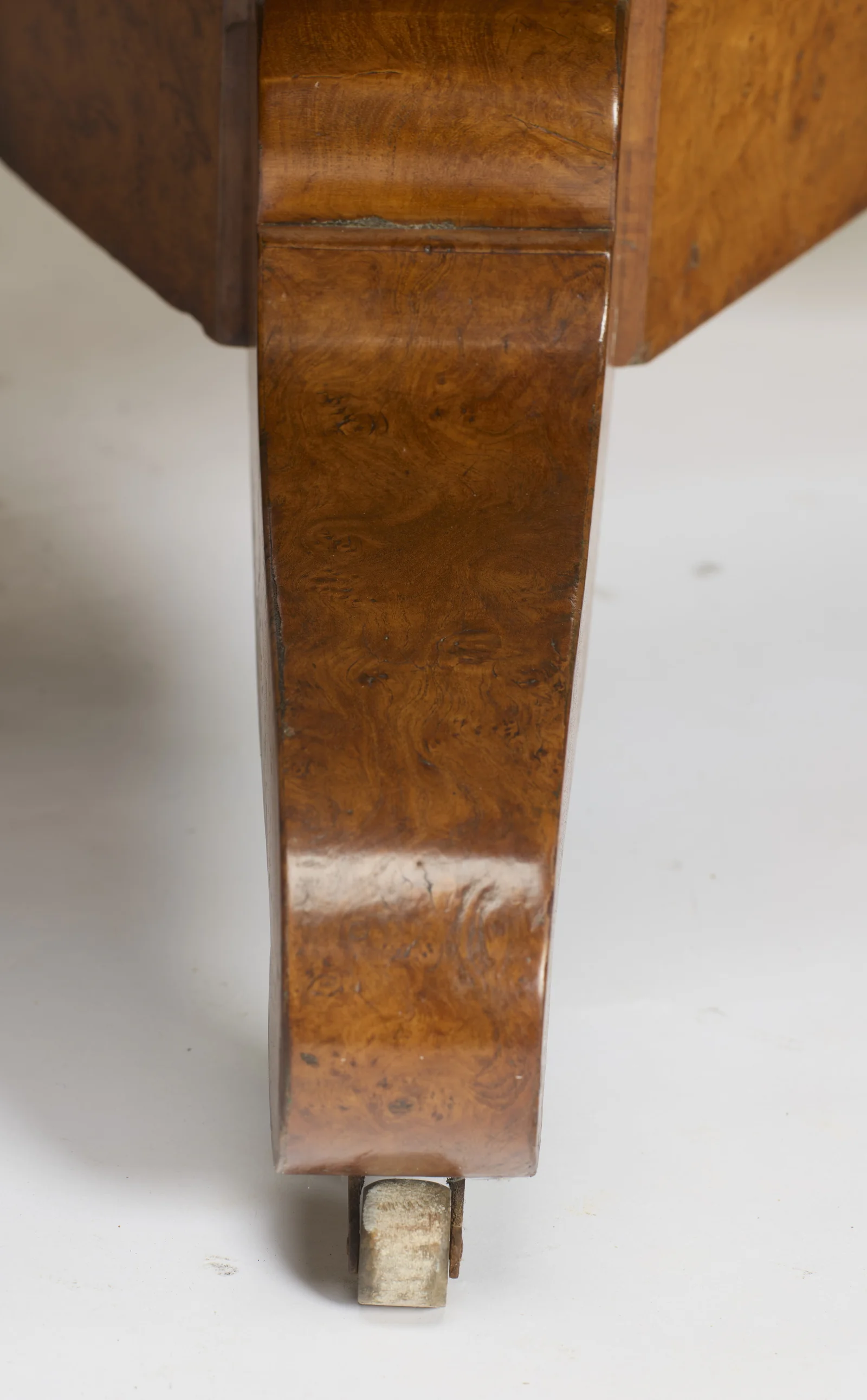 One scroll leg close up, the rippled burr figuring running down to a castor with a pale wheel.