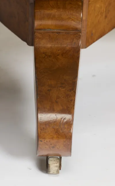 One scroll leg close up, the rippled burr figuring running down to a castor with a pale wheel.