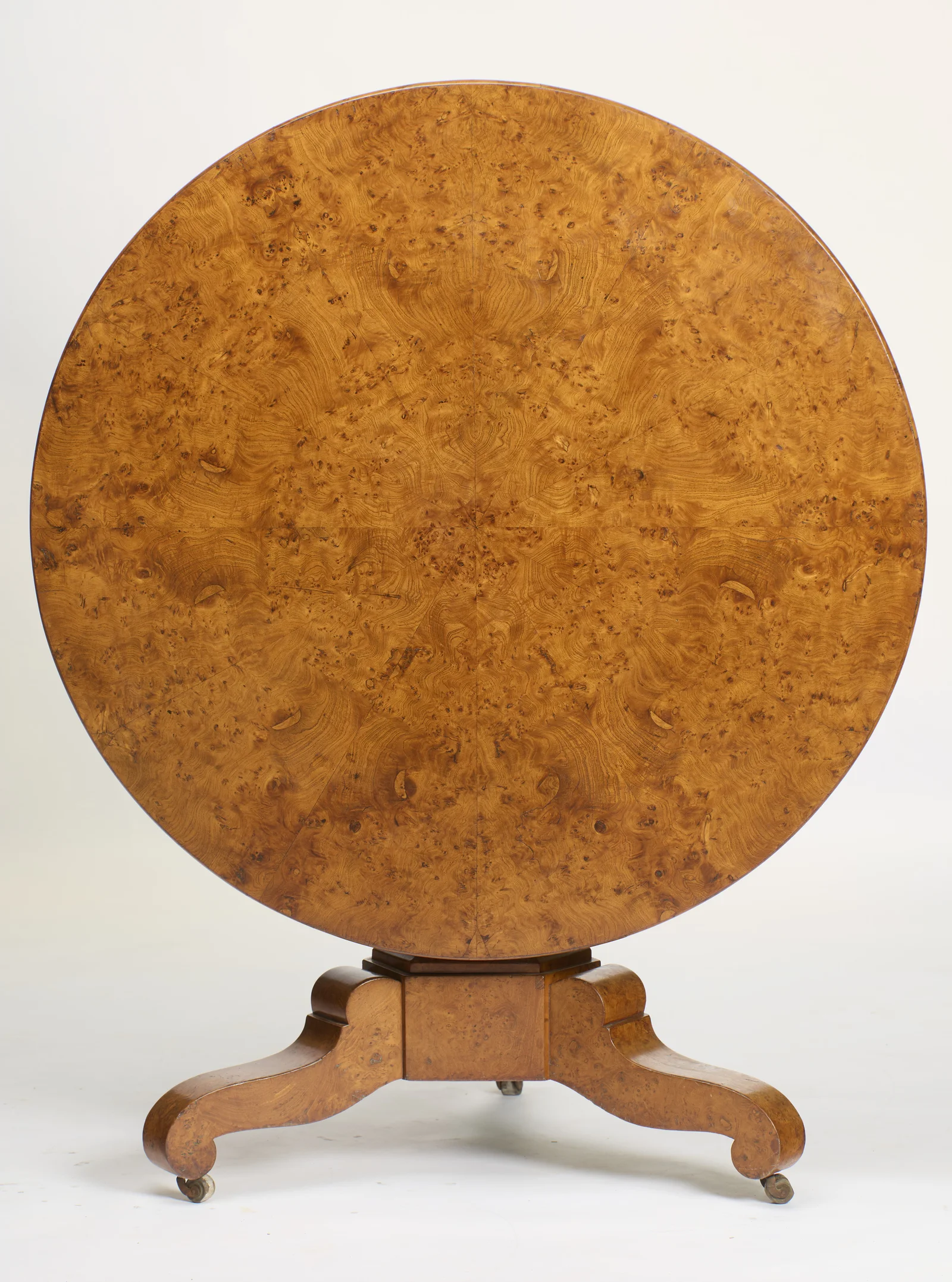 Tilted upright, the top presents a full disc of symmetrically matched burr figuring above the tripod base.