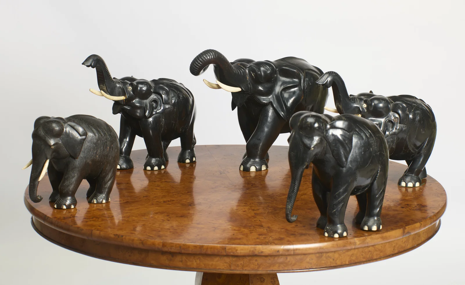 The five elephants spaced around the burr top, trunks variously raised, curled and lowered.