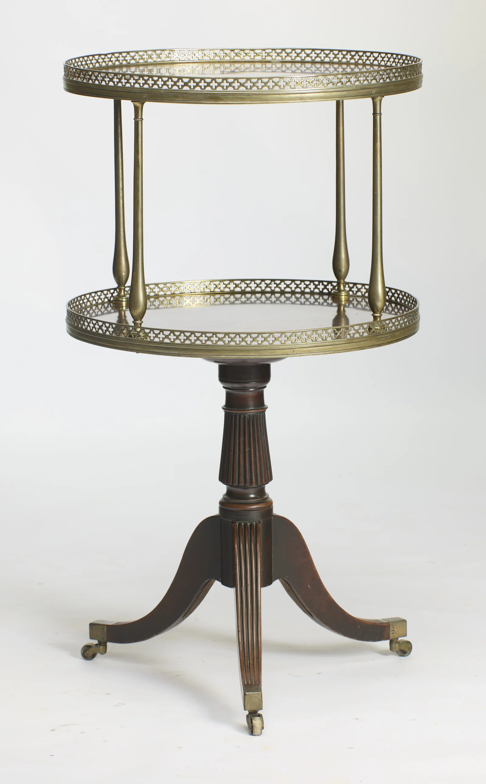 Both oval tiers with their pierced galleries, carried on baluster uprights over a reeded pedestal and three downswept legs on castors.
