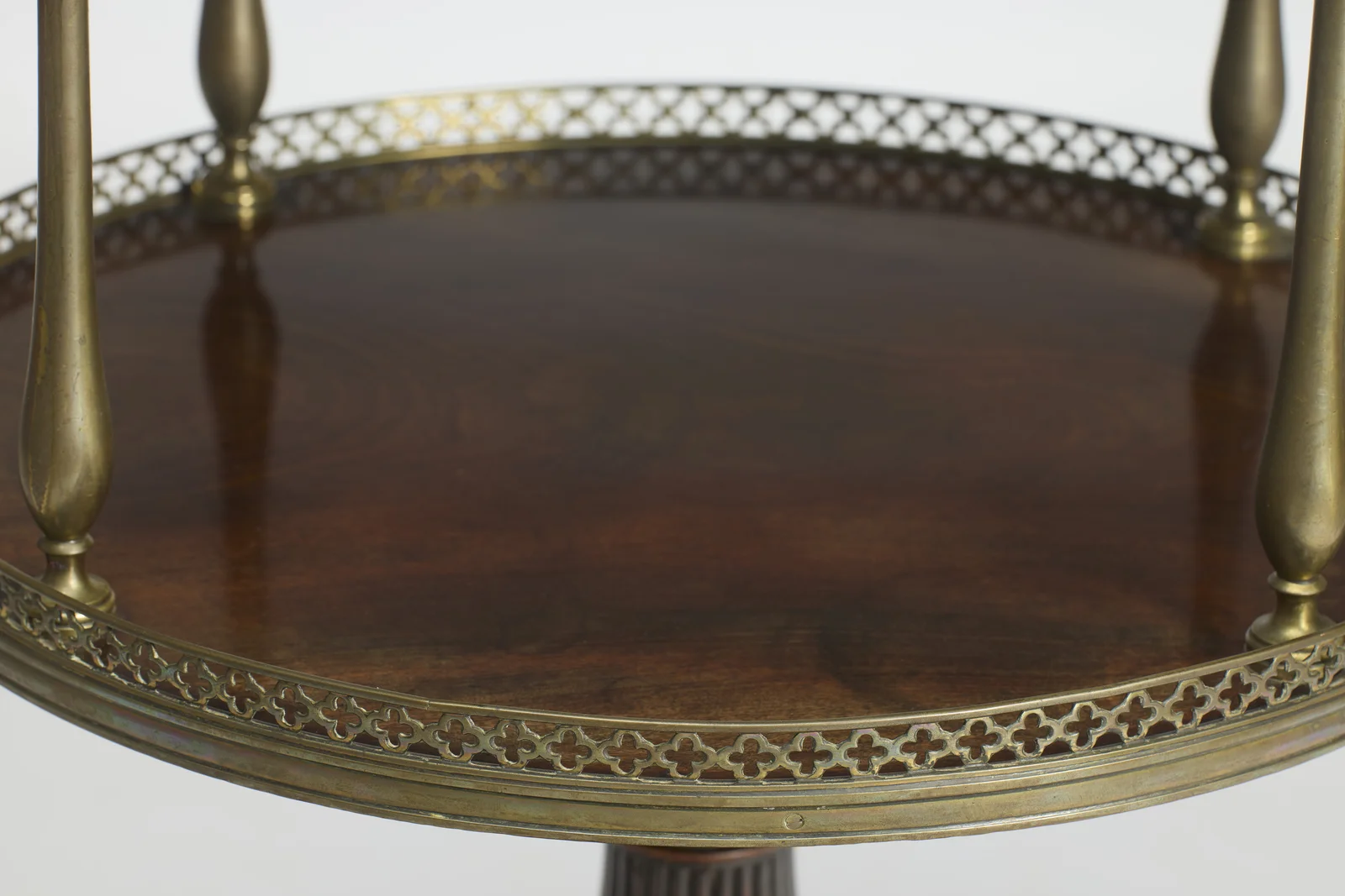 Strongly figured grain across the lower surface, ringed by the quatrefoil gallery where the baluster uprights meet the tier.