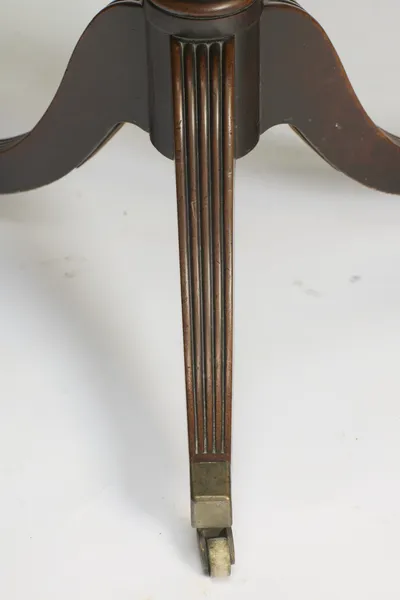 A downswept reeded leg finishing in a square metal cap and swivel castor, the reeded base of the pedestal above.