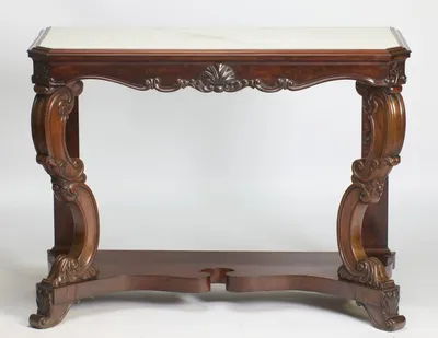The white marble top with canted front corners sits above a serpentine apron centred by a carved shell, raised on scrolled supports over a shaped platform base.