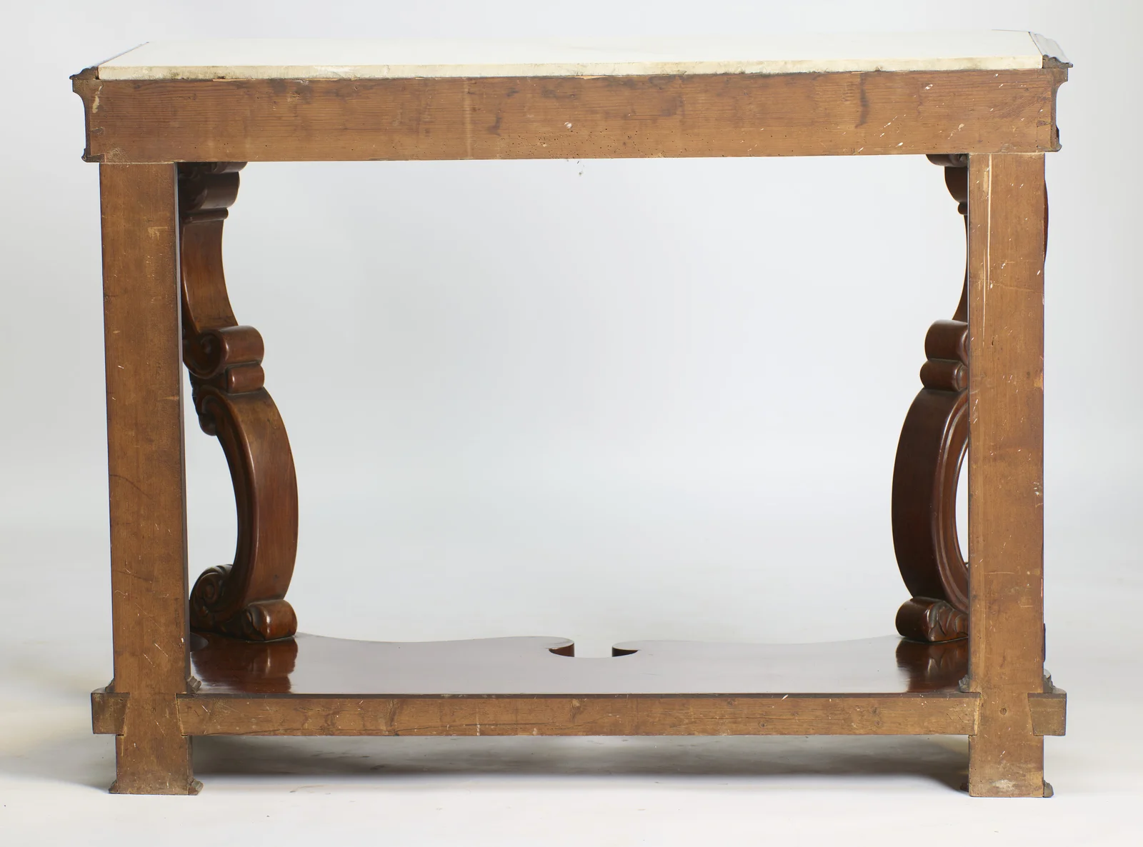 The back rail is left unfinished, and the shaped undertier and both scrolled supports are visible beneath the overhang of the marble.