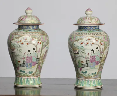 A closer angled view of the garden scenes, showing the domed covers with bud finials, the blue diaper collars and the flowering scroll ground flanking each panel.