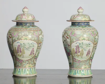 Each vase turned to the lobed oval panel painted with a river landscape of distant hills, sailing boats and pink and yellow trees, framed by dense flower and leaf scrolls.