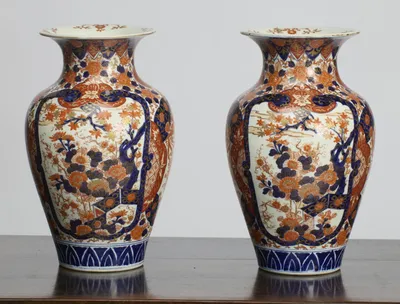 Both vases showing the large shaped panels painted with a flowering tree and massed blossom in blue, iron-red and gilt, above a band of blue stiff leaves at the foot.
