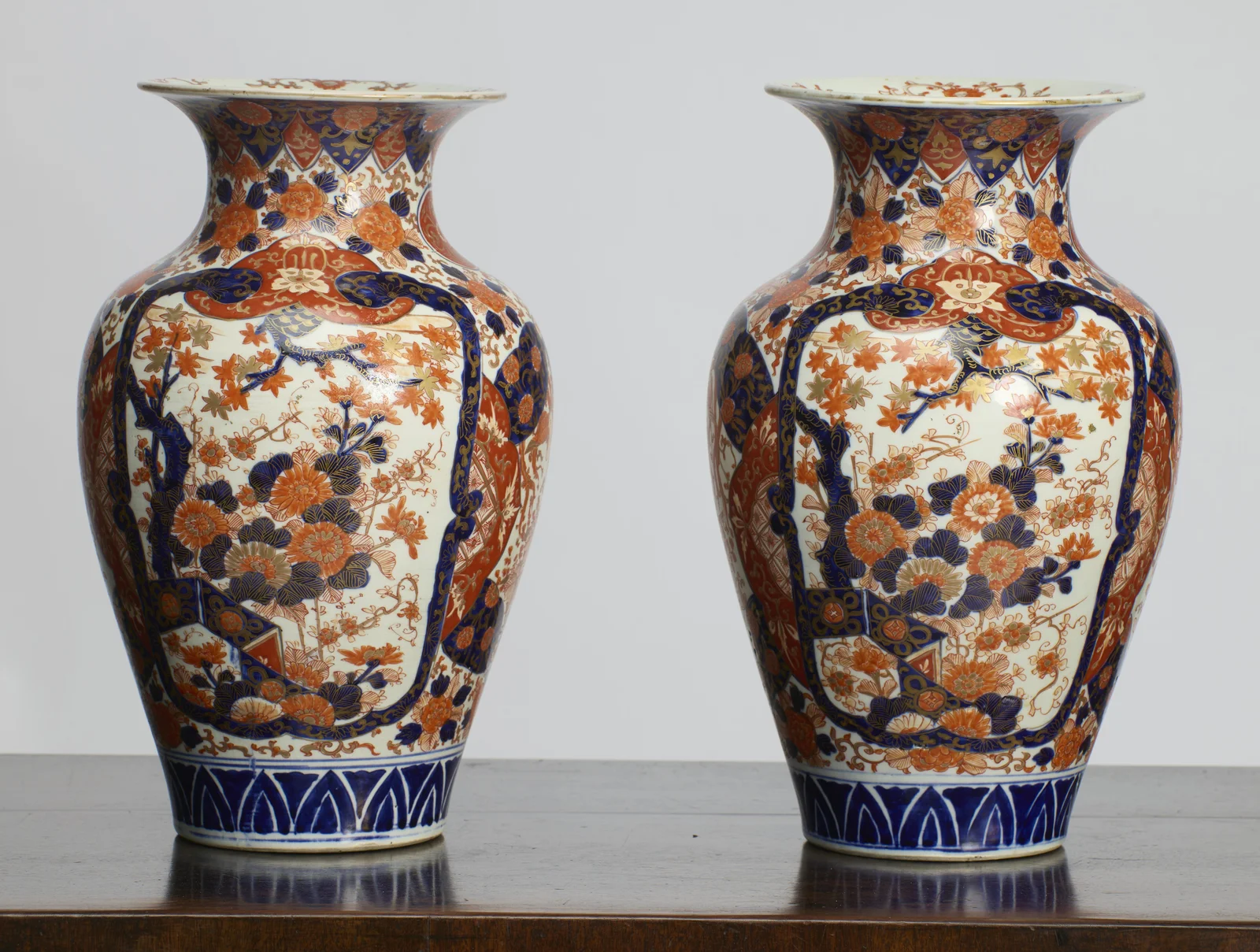 The pair turned slightly, showing the principal panels together with the patterned iron-red borders that frame them and the lappet border around each neck.
