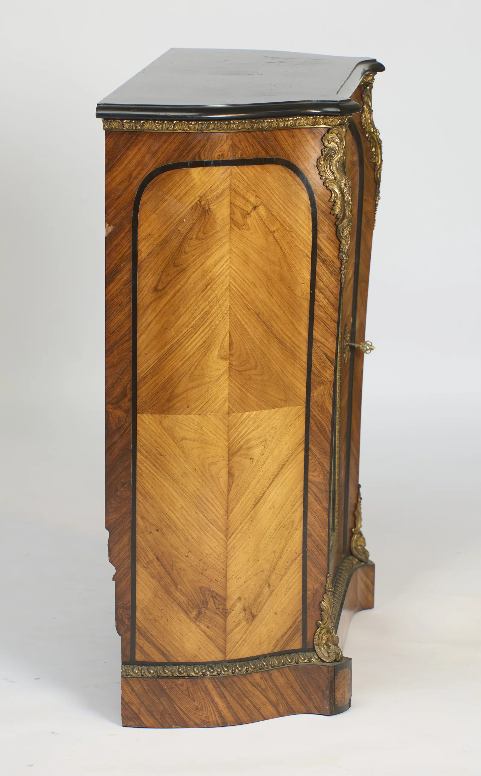 Quarter-matched veneer inside a shaped ebonised-line border, with the egg-and-dart gilt band running along the plinth.