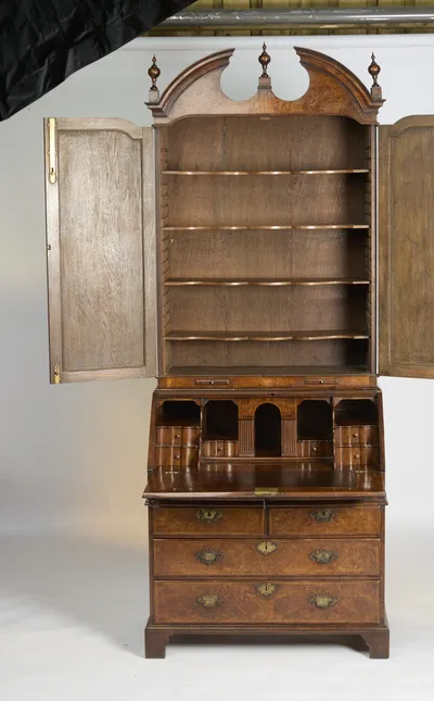 Both mirror doors stand open on a shelved upper cabinet, with the fall down to show the fitted interior below.