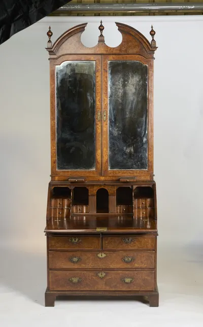 The fall rests open on its pull-out supports, showing scalloped small drawers and pigeonholes around an arched centre and a tooled writing surface.