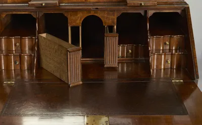 Scalloped drawers and open pigeonholes flank a fluted arched centre; two fluted-fronted compartments sit out of their housings on the tooled writing surface.