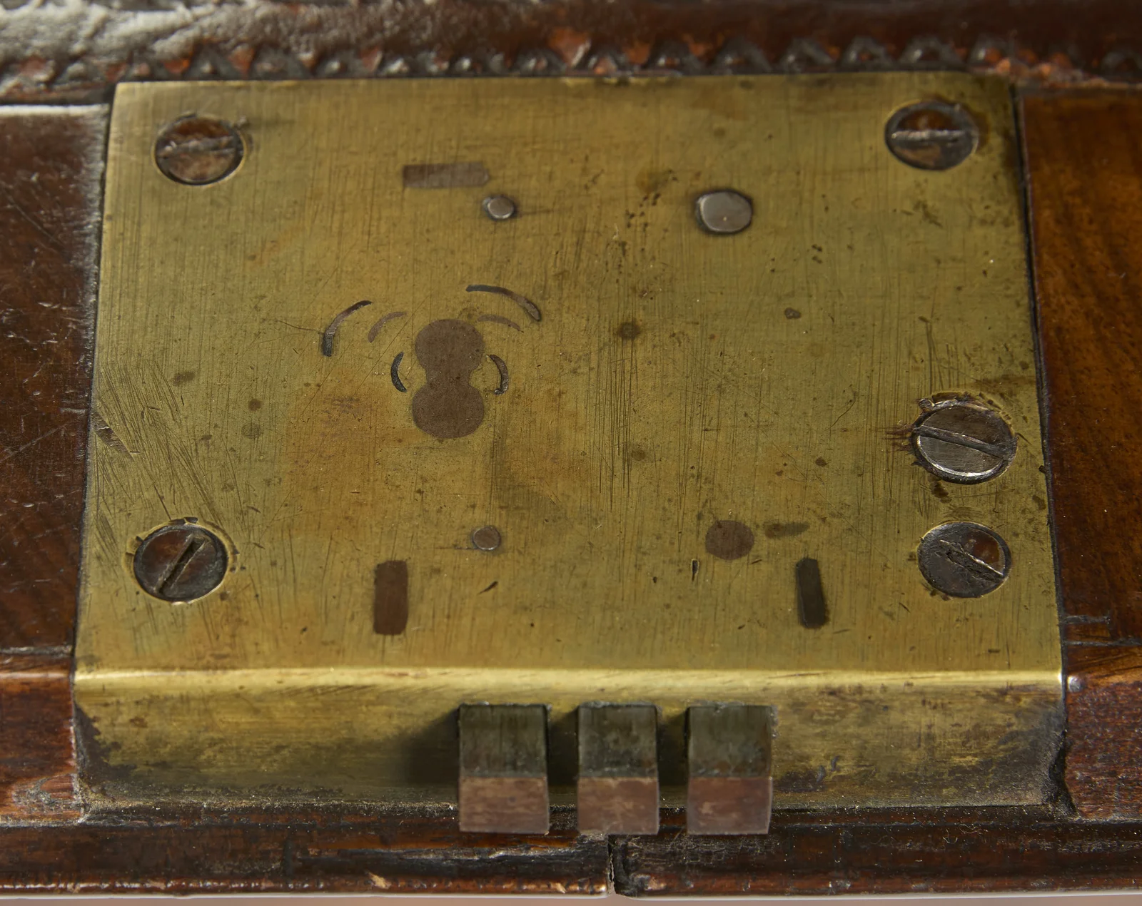 The gilt-metal lock plate on the inside edge of the fall, beside the tooled border of the writing surface.