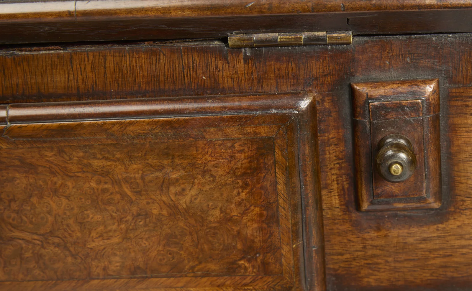 A turned knob on the pull-out support beneath the open fall, beside a moulded burr panel.