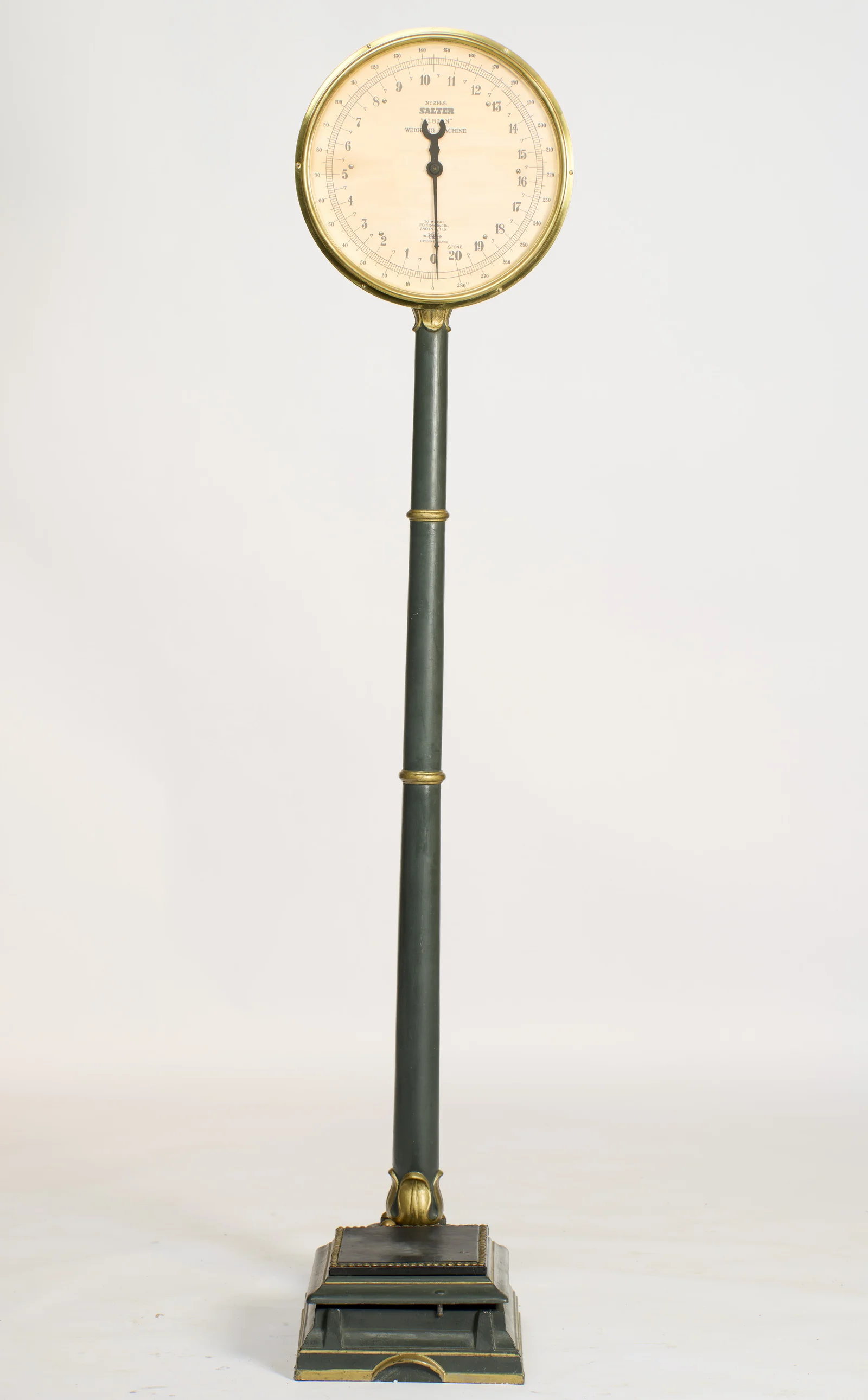 The full machine, the brass-bezelled dial raised on a green column with gilt collars above the studded black platform and stepped base.