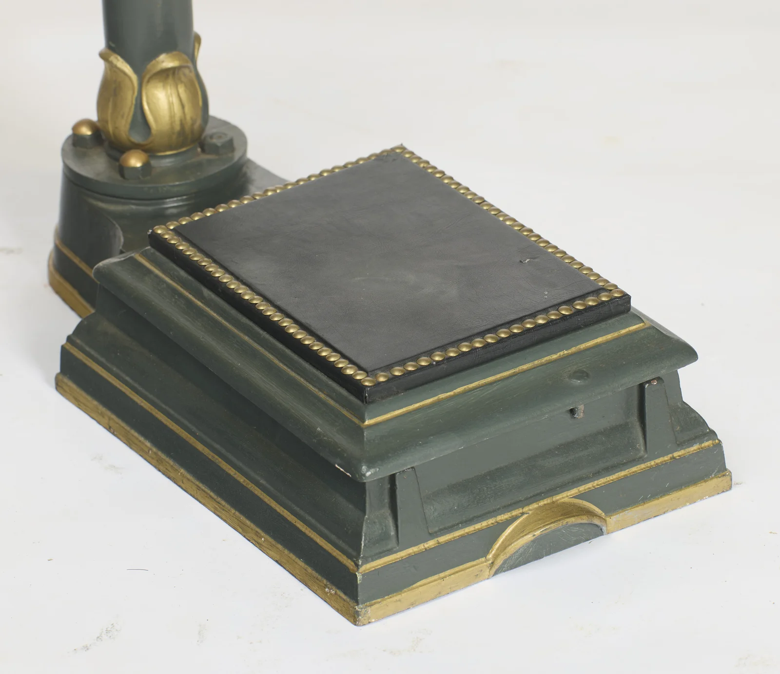 The black standing pad bordered with a run of beaded gilt studs, on a stepped base lined in gilt, the leaf-cast collar at the column foot beyond.
