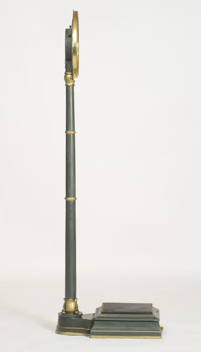 In profile the column rises with a slight backward rake, the dial edge-on above and the platform extending to the side.