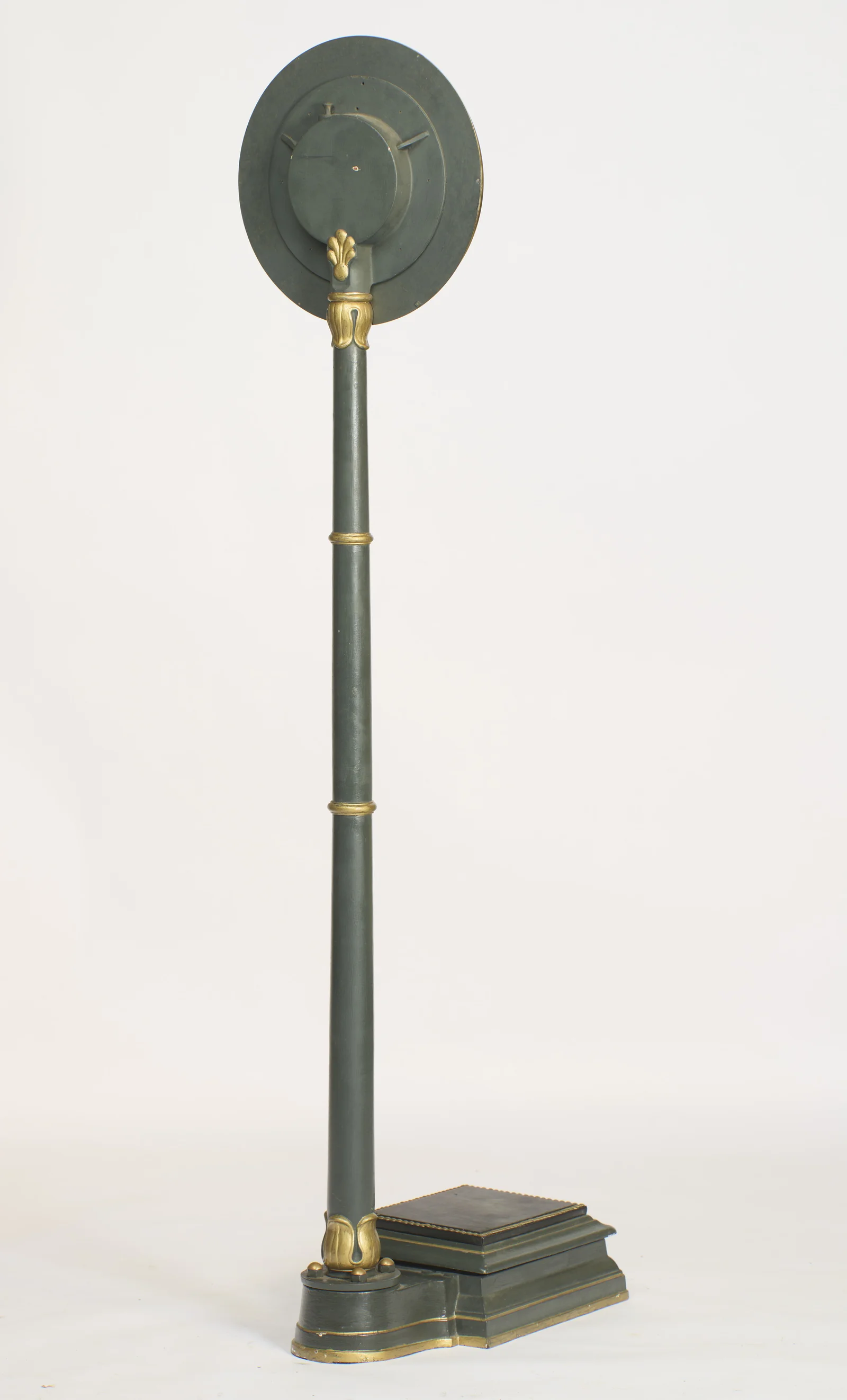 The plain painted back of the dial with its raised circular housing, a gilt palmette at the junction with the column.