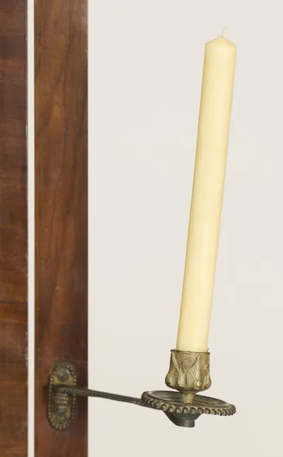 A swivelling metal arm carries a beaded circular drip-pan and a nozzle cast with leaves, mounted on an oval beaded backplate with the turned tilt knob below.