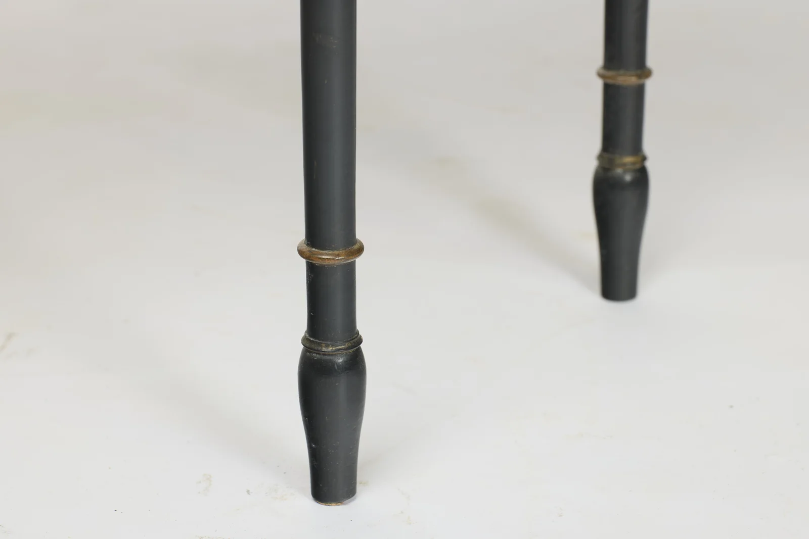 Gilt-lined ring turnings above swelled tapering feet, with rubbing and small losses to the black finish.
