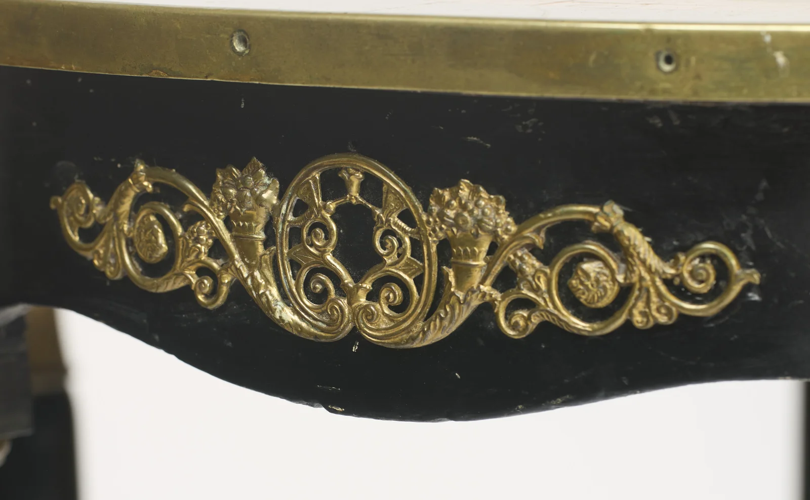 A pierced scrolling mount with flower-filled cornucopias and rosettes, the tall gilt collars of the flanking legs visible below.