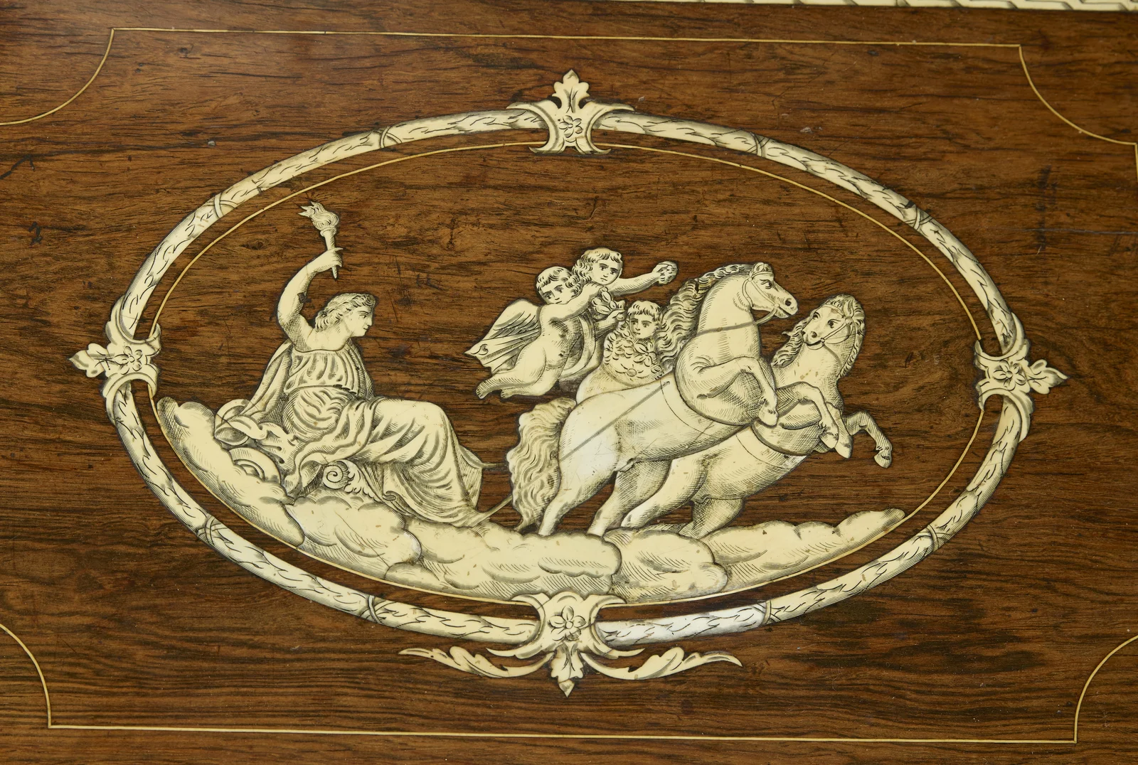 An oval laurel band enclosing a draped figure raising a torch, carried on clouds behind two rearing horses with winged child attendants; fine cracks run across the engraved panel.