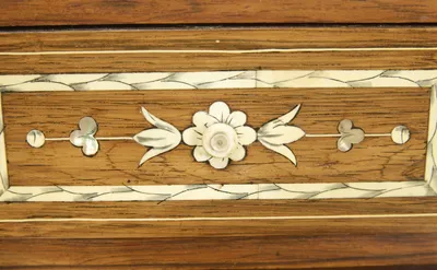 A small drawer with a turned flower-head knob set on an inlaid flower, between tulip sprays and iridescent trefoils; areas of discoloration to the pale banding at the border.
