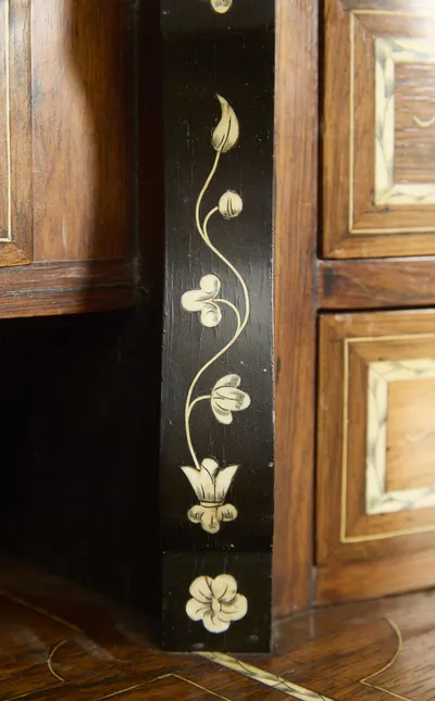 An ebonised pier beside the open recess, inlaid with a single climbing stem of tulips, buds and trefoils rising from a flowerhead at its foot.